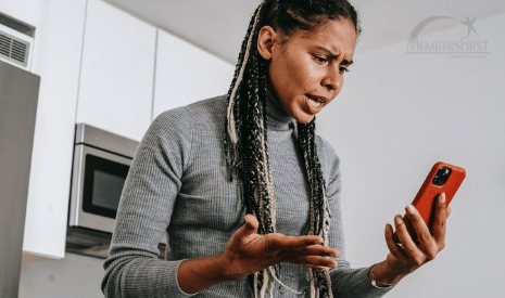 African American woman with braids in grey shirt looking annoying at her phone